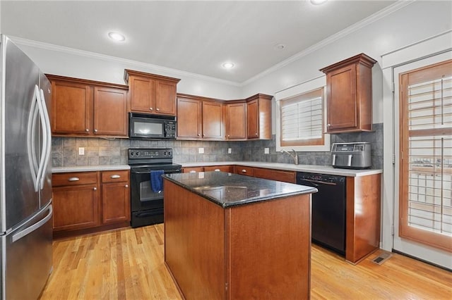 kitchen with a kitchen island, decorative backsplash, light wood finished floors, and black appliances