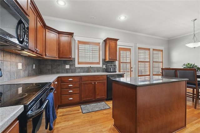 kitchen with ornamental molding, light wood-type flooring, a center island, backsplash, and black appliances
