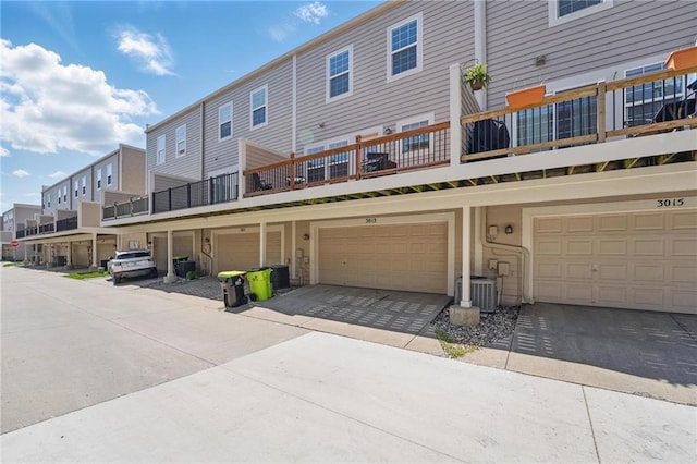 exterior space featuring an attached garage, a residential view, and cooling unit
