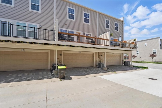 back of house with central air condition unit and an attached garage