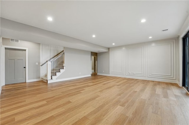 basement with stairway, light wood-style flooring, recessed lighting, baseboards, and a decorative wall
