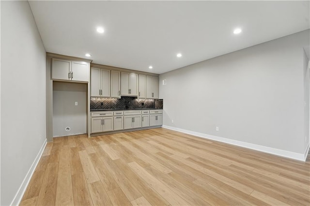 kitchen featuring decorative backsplash, light wood-type flooring, dark countertops, baseboards, and recessed lighting