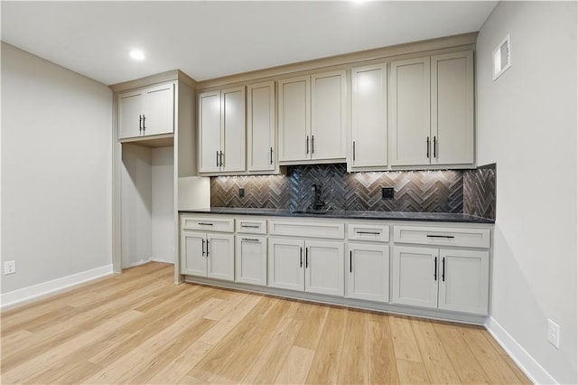 kitchen featuring a sink, baseboards, dark countertops, decorative backsplash, and recessed lighting