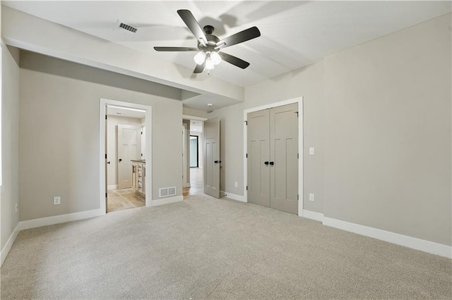 unfurnished bedroom featuring light carpet, baseboards, ensuite bath, ceiling fan, and a closet