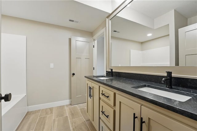 full bath featuring baseboards, double vanity, wood finish floors, recessed lighting, and a bathtub