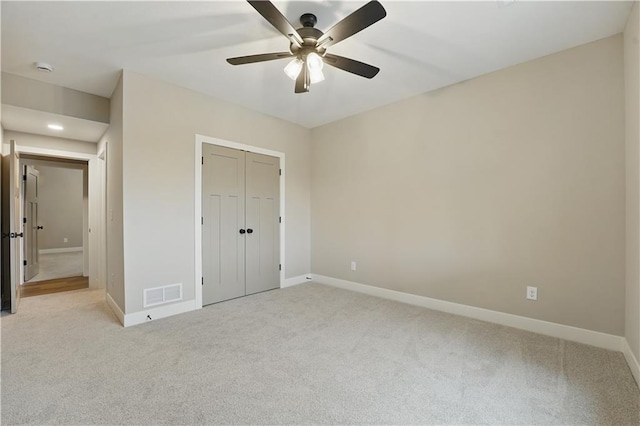 unfurnished bedroom with light carpet, baseboards, a closet, and a ceiling fan