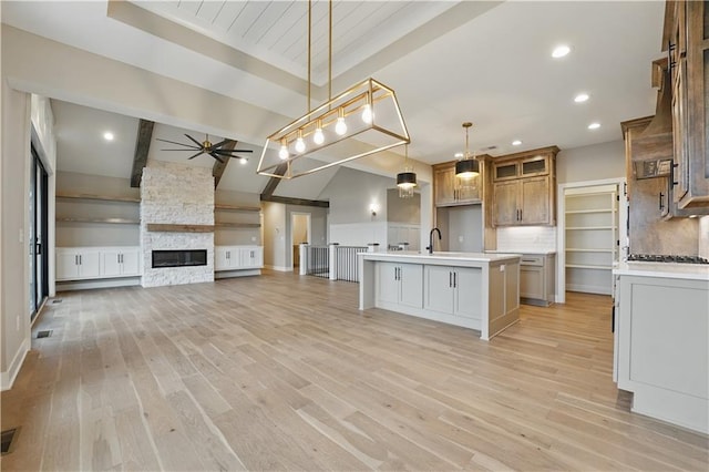 kitchen featuring an island with sink, light wood finished floors, light countertops, ceiling fan, and recessed lighting