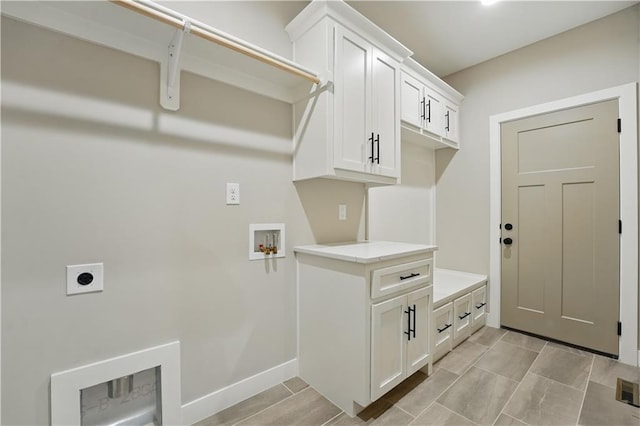 clothes washing area featuring hookup for an electric dryer, washer hookup, cabinet space, and baseboards