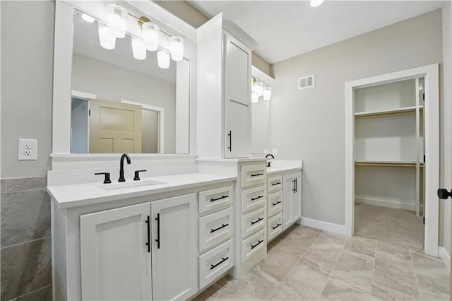 full bathroom with double vanity and a walk in closet
