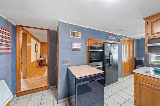 4401 N Holmes St, Kansas City, MO 64116 - kitchen with a textured ceiling, black appliances, light tile patterned flooring, light countertops, and under cabinet range hood