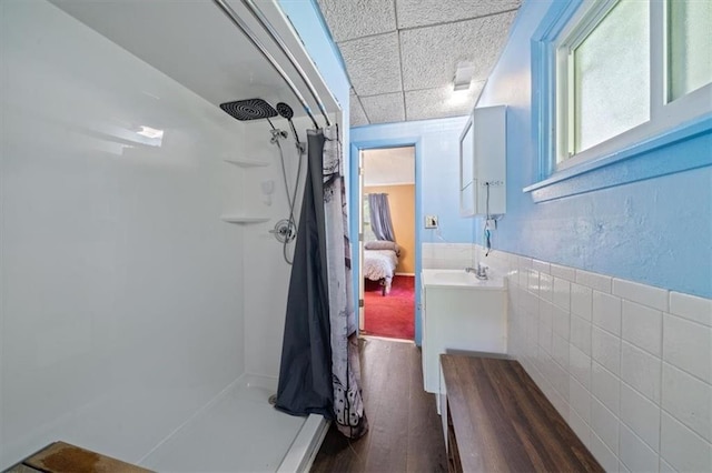 4401 N Holmes St, Kansas City, MO 64116 - bathroom featuring wood finished floors, vanity, a paneled ceiling, and a walk in shower