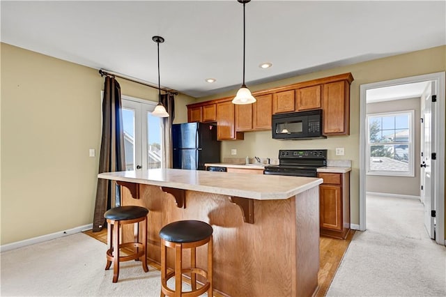 3205 SW Rockbridge Dr, Lees Summit, MO 64081 - kitchen featuring a breakfast bar area, brown cabinets, a sink, light countertops, and black appliances