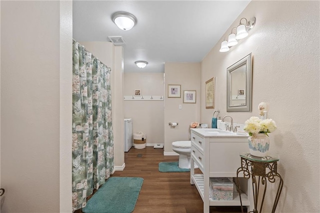 bathroom featuring vanity, a shower with curtain, toilet, visible vents, and wood finished floors