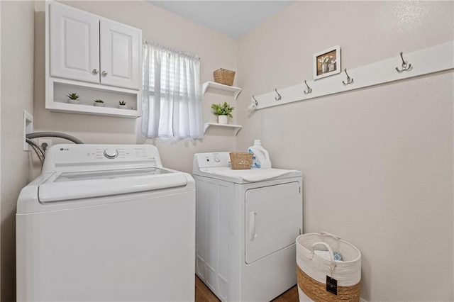 clothes washing area with independent washer and dryer, wood finished floors, and cabinet space