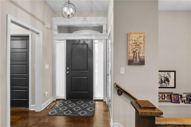 entrance foyer featuring visible vents, baseboards, an inviting chandelier, and wood finished floors