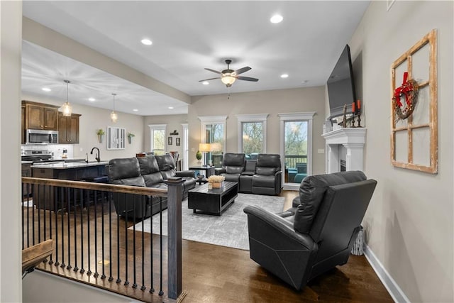 living area with recessed lighting, baseboards, a ceiling fan, and a healthy amount of sunlight