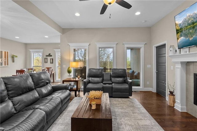 living room with a tiled fireplace, ceiling fan, recessed lighting, and dark wood-style floors