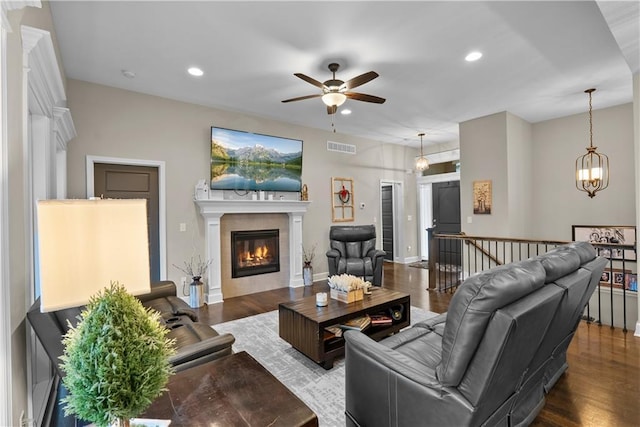 living area with a glass covered fireplace, a ceiling fan, visible vents, recessed lighting, and wood finished floors