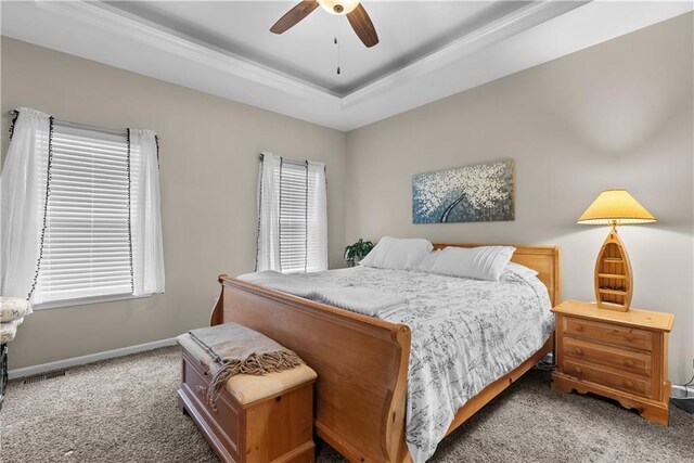 bedroom with a tray ceiling, baseboards, a ceiling fan, and carpet