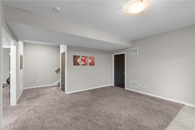 finished below grade area featuring carpet flooring, visible vents, and stairway