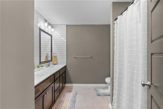 full bath featuring baseboards, a sink, toilet, double vanity, and tile patterned flooring