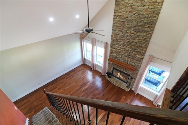 611 NW 1421st Rd, Holden, MO 64040 - unfurnished living room featuring a stone fireplace, baseboards, ceiling fan, wood finished floors, and healthy amount of natural light