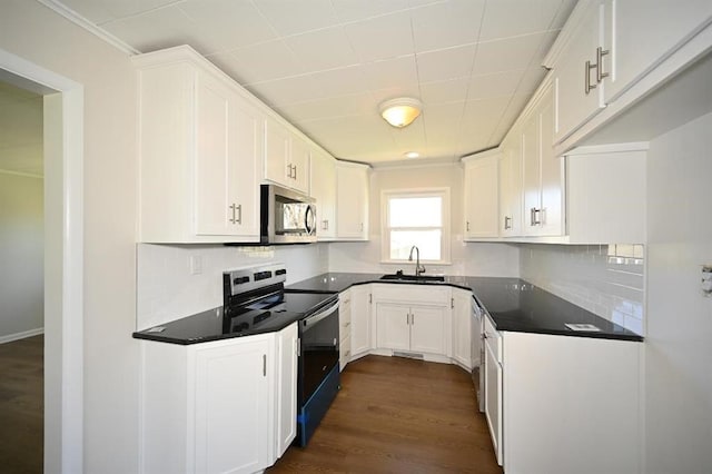 kitchen featuring a sink, dark countertops, white cabinetry, stainless steel appliances, and decorative backsplash