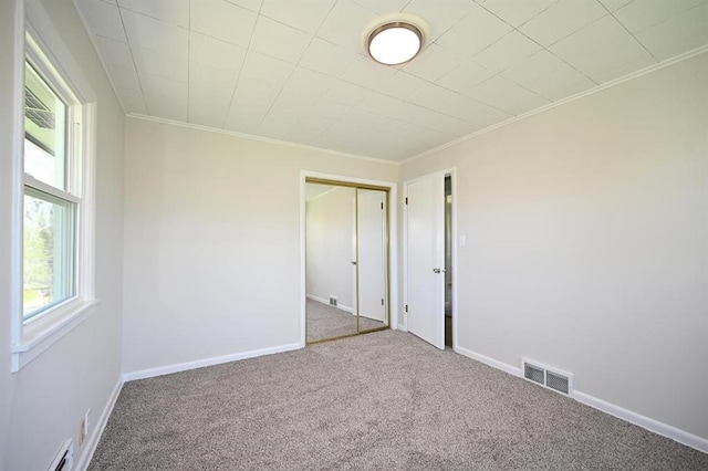 unfurnished bedroom with crown molding, carpet, and visible vents