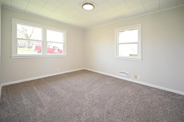 unfurnished room with a wealth of natural light, carpet flooring, and ornamental molding