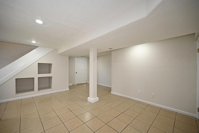 finished below grade area featuring built in features, baseboards, recessed lighting, and light tile patterned flooring