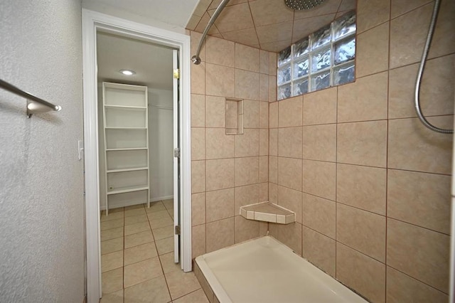 bathroom featuring tile patterned flooring, a spacious closet, a stall shower, and a textured wall