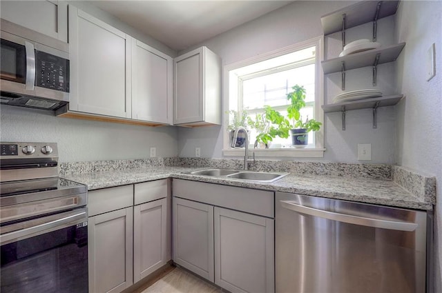 1610 E 37th St, Kansas City, MO 64109 - kitchen with light stone counters, open shelves, a textured wall, a sink, and appliances with stainless steel finishes