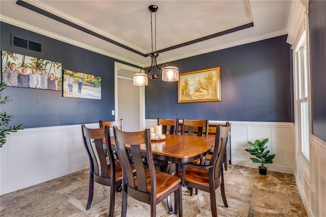 25477 Crestview Dr, Paola, KS 66071 - dining room featuring a decorative wall, stone finish floors, a wainscoted wall, crown molding, and a tray ceiling