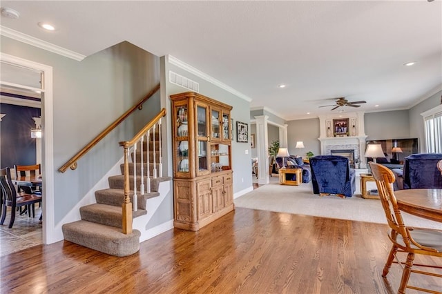 25477 Crestview Dr, Paola, KS 66071 - dining room featuring ceiling fan, stairs, wood finished floors, a fireplace, and ornamental molding