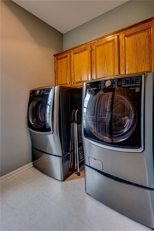 25477 Crestview Dr, Paola, KS 66071 - washroom featuring cabinet space, independent washer and dryer, light tile patterned flooring, and baseboards