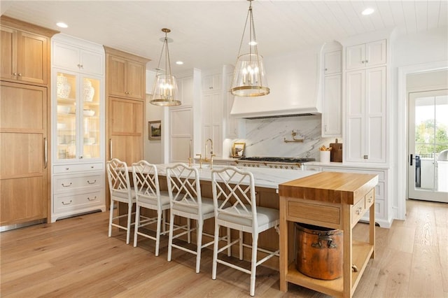 11316 W 170th Ter, Overland Park, KS 66221 - kitchen featuring light wood-style floors, tasteful backsplash, a large island, custom exhaust hood, and a breakfast bar area
