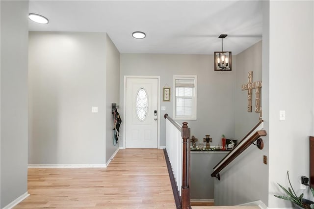 entrance foyer with light wood-type flooring, a chandelier, and baseboards