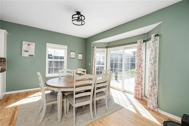 dining space with light wood-type flooring and baseboards