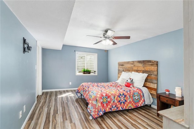 bedroom with wood finished floors, baseboards, and a ceiling fan