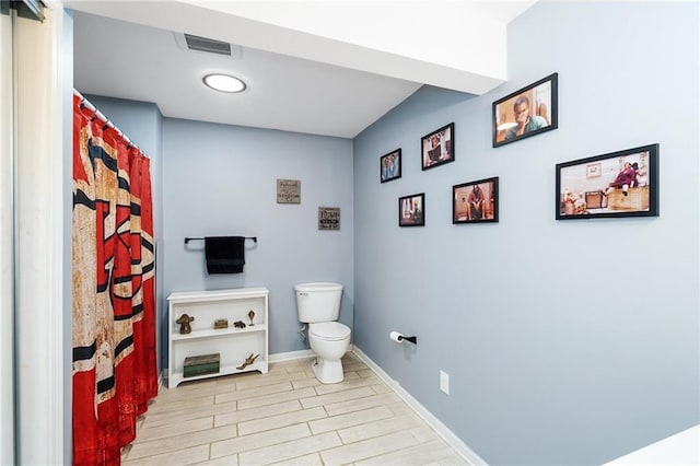 full bath with toilet, wood finished floors, baseboards, and curtained shower