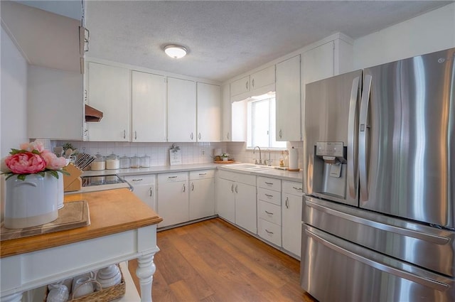 626 N 83rd Ter, Kansas City, KS 66112 - kitchen featuring exhaust hood, stainless steel fridge with ice dispenser, a sink, light wood-style floors, and tasteful backsplash