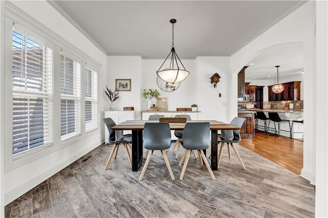 1237 Hillmann Ln, Warrensburg, MO 64093 - dining area with crown molding, light wood-type flooring, and arched walkways