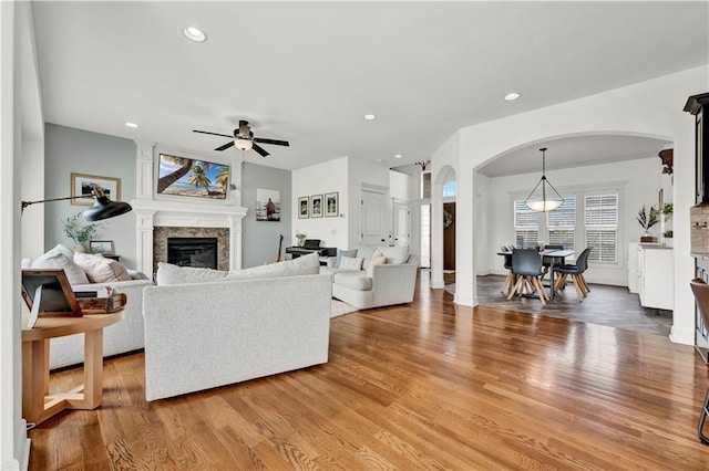 1237 Hillmann Ln, Warrensburg, MO 64093 - living area featuring arched walkways, ceiling fan, a glass covered fireplace, light wood-style floors, and recessed lighting