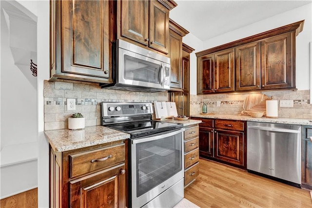 1237 Hillmann Ln, Warrensburg, MO 64093 - kitchen featuring stainless steel appliances, light wood-type flooring, decorative backsplash, and light stone counters