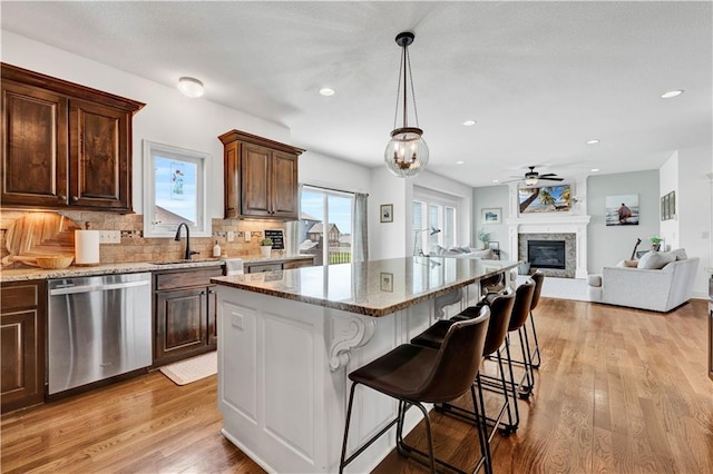 1237 Hillmann Ln, Warrensburg, MO 64093 - kitchen featuring stainless steel dishwasher, light stone counters, a glass covered fireplace, ceiling fan, and tasteful backsplash