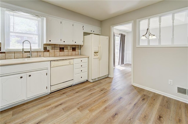 kitchen with white cabinets, an inviting chandelier, a sink, light wood-type flooring, and white appliances