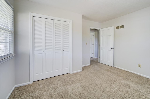 unfurnished bedroom featuring visible vents, a closet, baseboards, and carpet floors