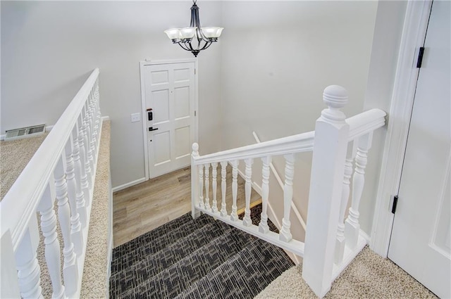 stairs featuring a notable chandelier, baseboards, and visible vents