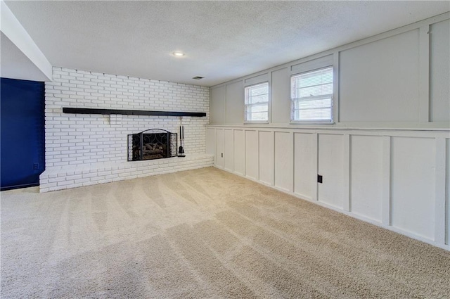 unfurnished living room with a textured ceiling, a decorative wall, a fireplace, and carpet floors