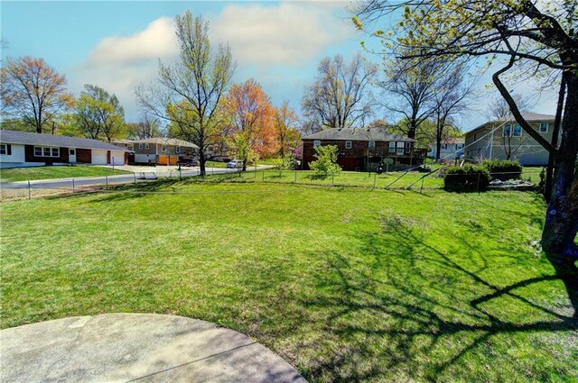 view of yard featuring a garage, driveway, and fence
